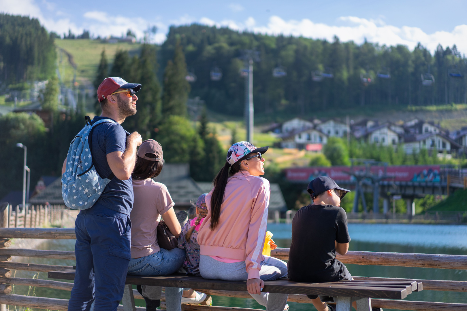 Family sitting on a bench looking out over a green valley resort town