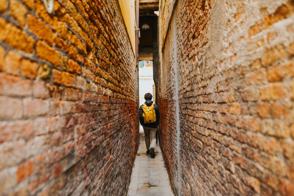 Traveler with a backpack walking through a narrow brick passage