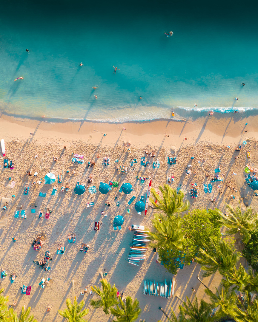 Aerial view of a turquoise beach lined with rows of umbrellas