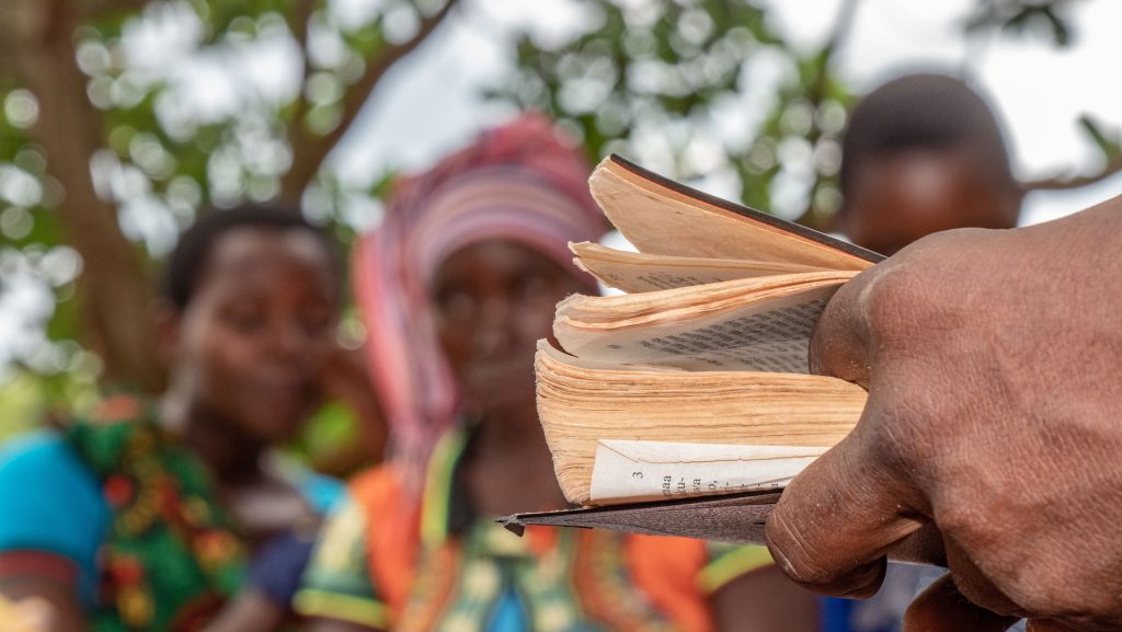 A group reading together from an open book outdoors