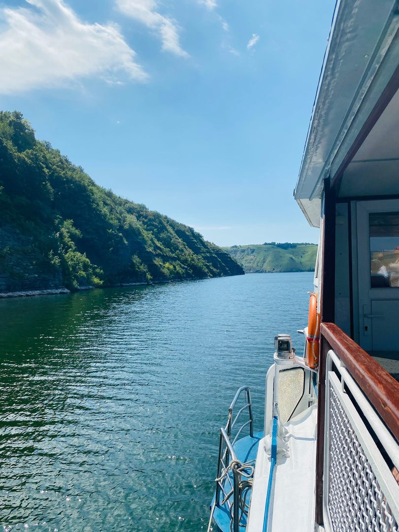The view from a boat deck along a steep green shoreline