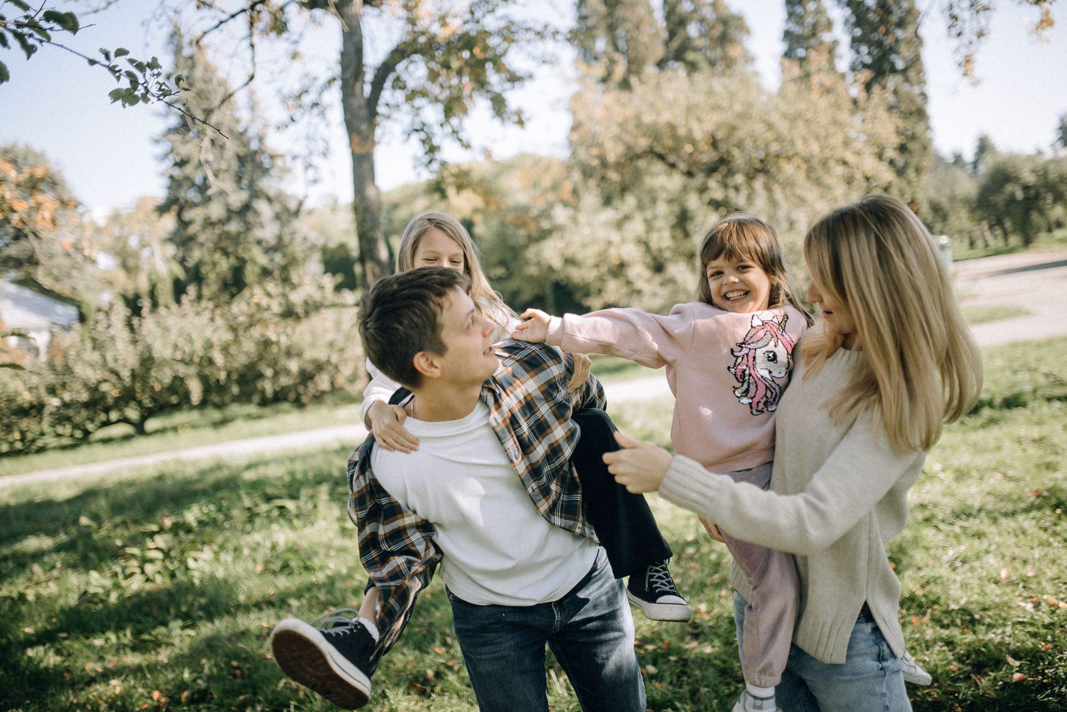Parents lifting a small child while playing together in a park