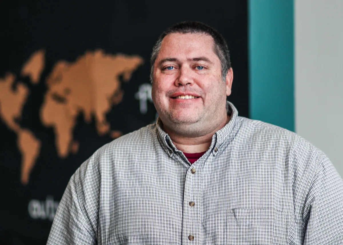 Grant Haynes, founder of MinistryVacations.org, in front of a wall-sized world map