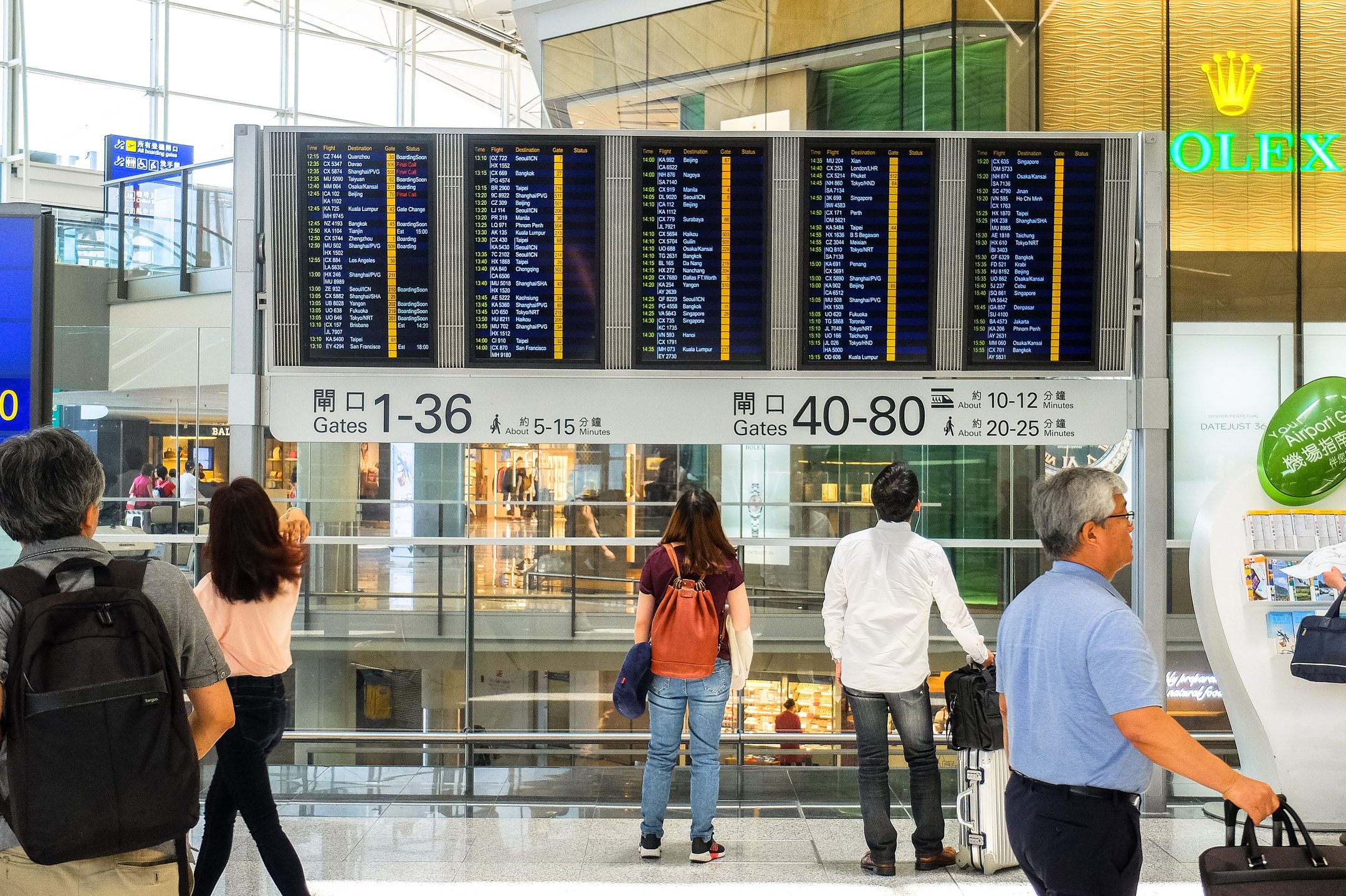 Travellers reading a departure board in an airport terminal
