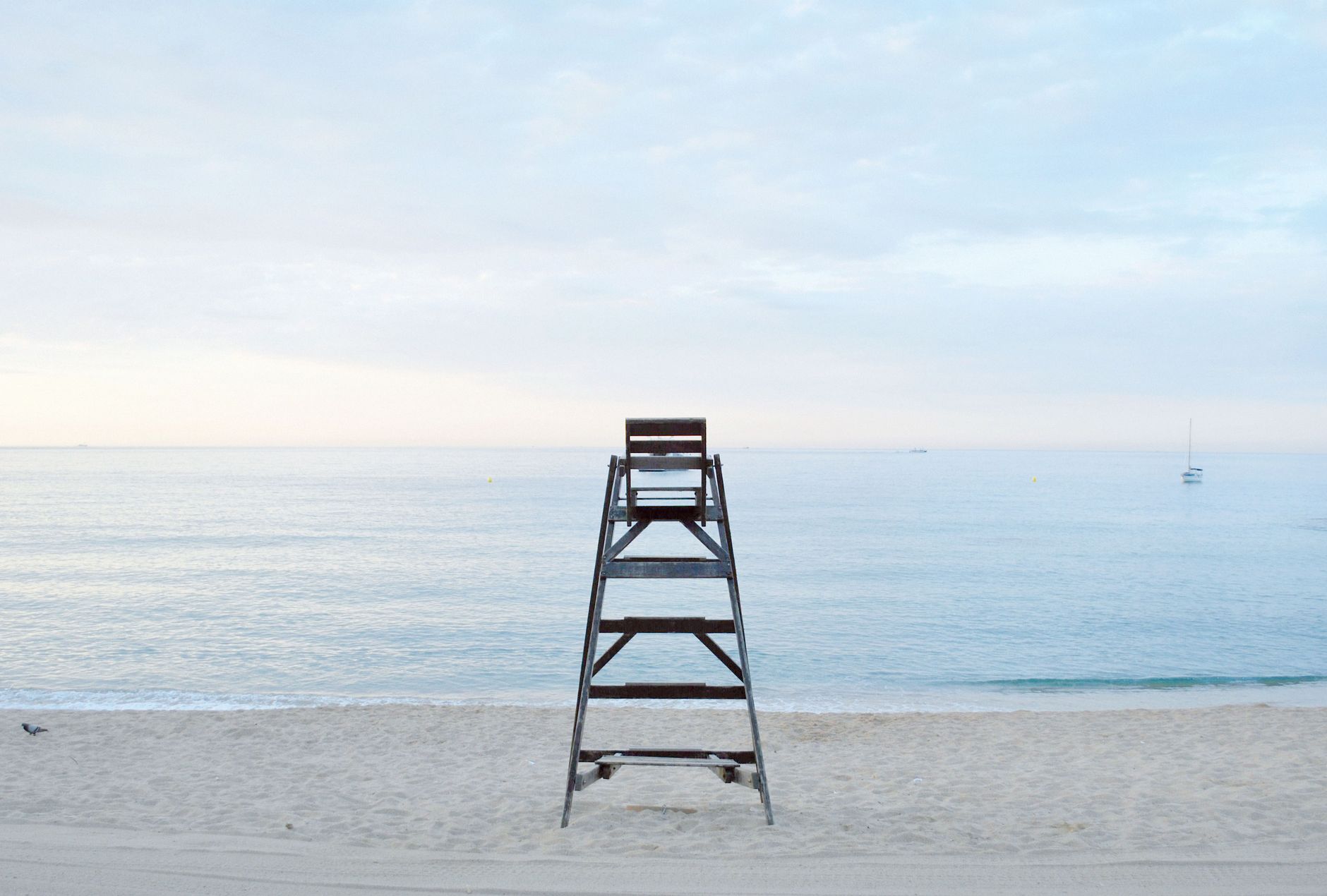 An empty beach at first light with a lifeguard chair facing the sea