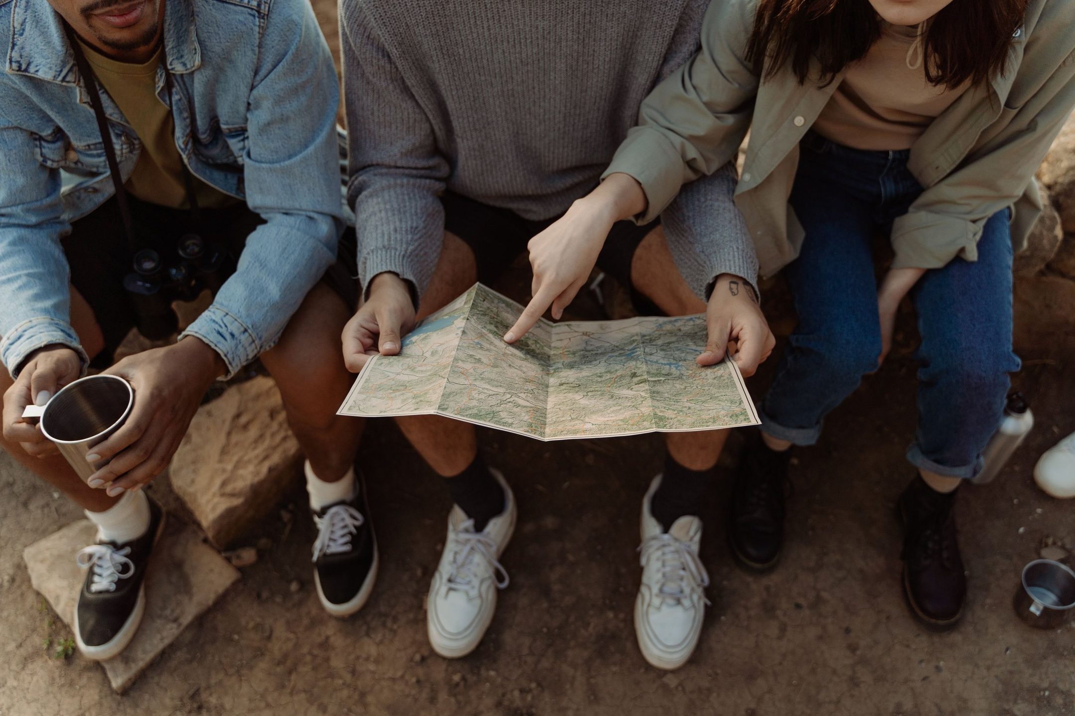 Travellers sitting together with coffee, working out a route on an open map