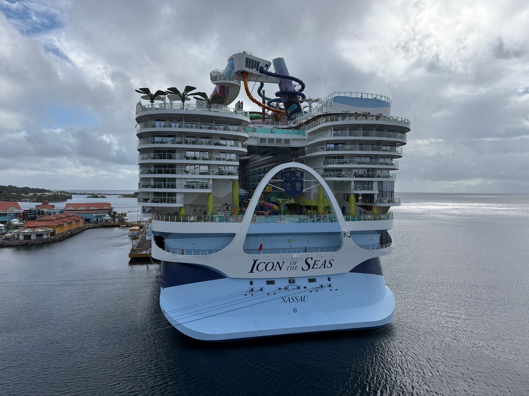 The cruise ship *Icon of the Seas* sits docked at a port under cloudy skies