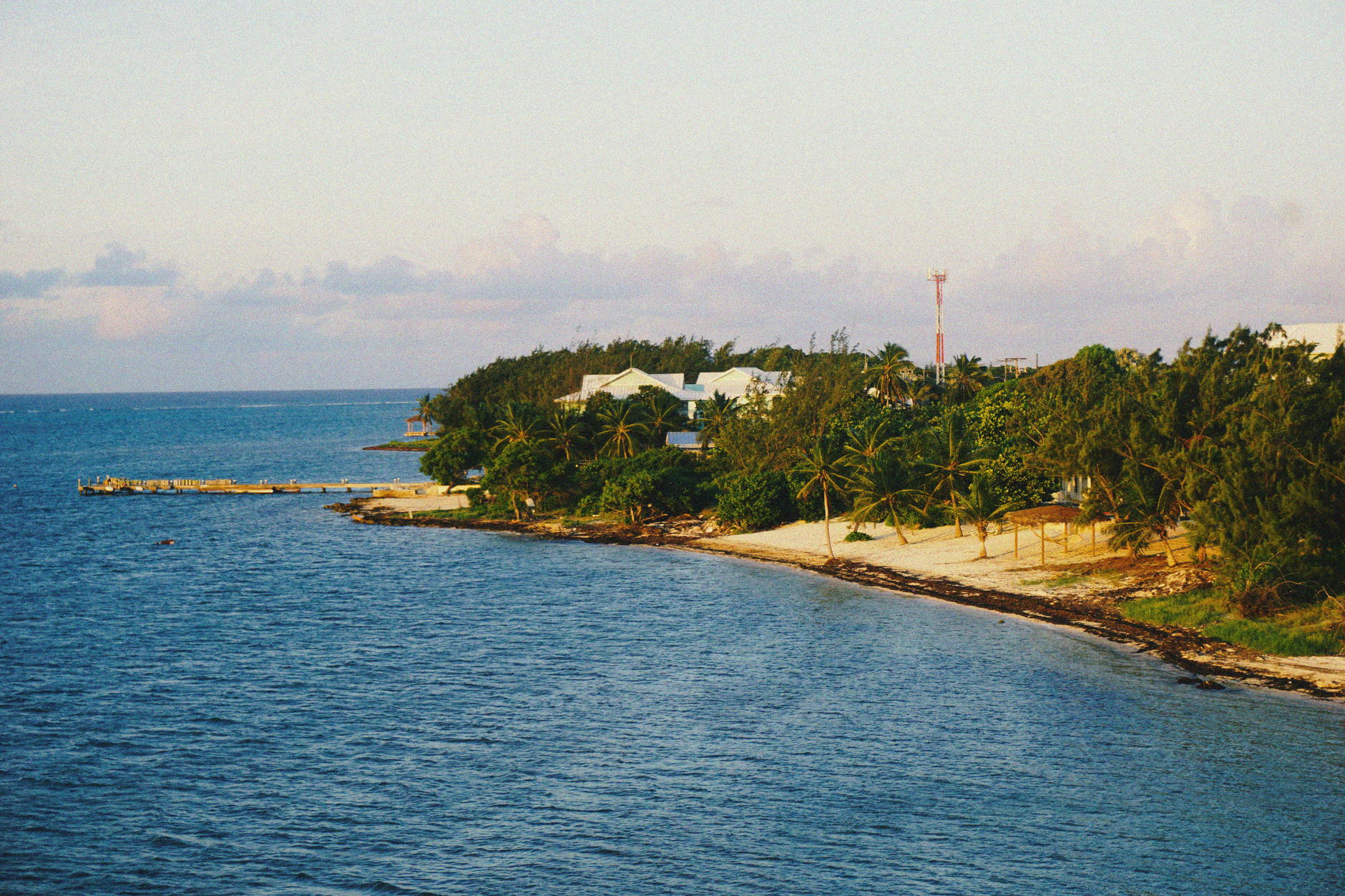 A low wooded point with scattered buildings seen across calm water