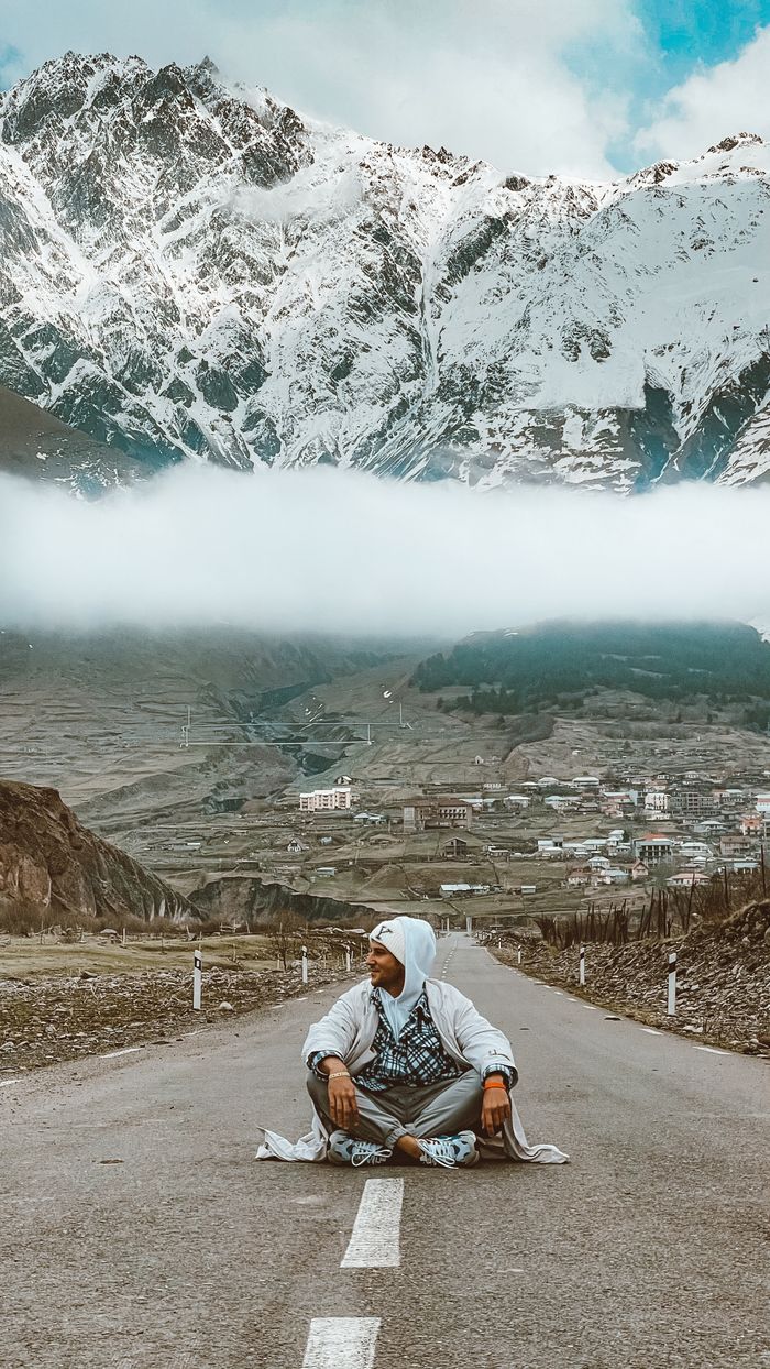 gallery-2 A man pauses on a mountain road with snowy peaks in view, embodying the spirit of ministry travel and renewal.